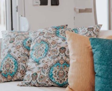 Aksamitne poduszki do szarej kanapy — paleta kolorów i triki stylistów, które odmienią salon